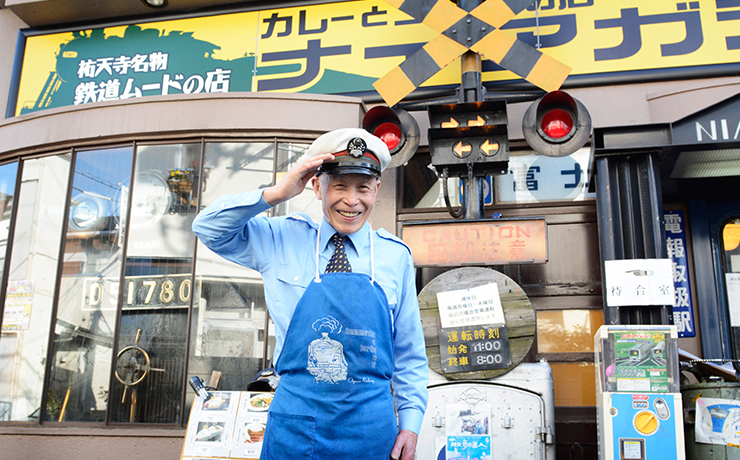 「カレーステーション ナイアガラ」の前で敬礼する内藤さん