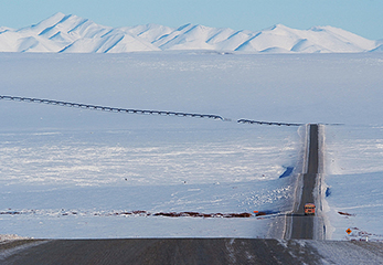 真っ白な雪の中のダルトンハイウェイとアラスカ原油パイプライン