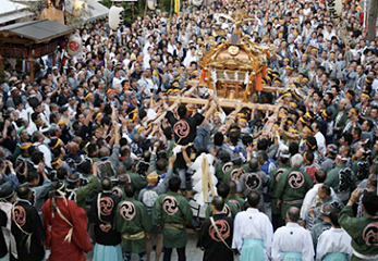 「だらだら祭り」で大勢の人が神輿を担ぐ様子