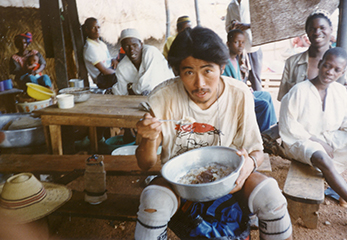 ギニアの食堂で、洗面器によそられた料理を食べる石田さん。